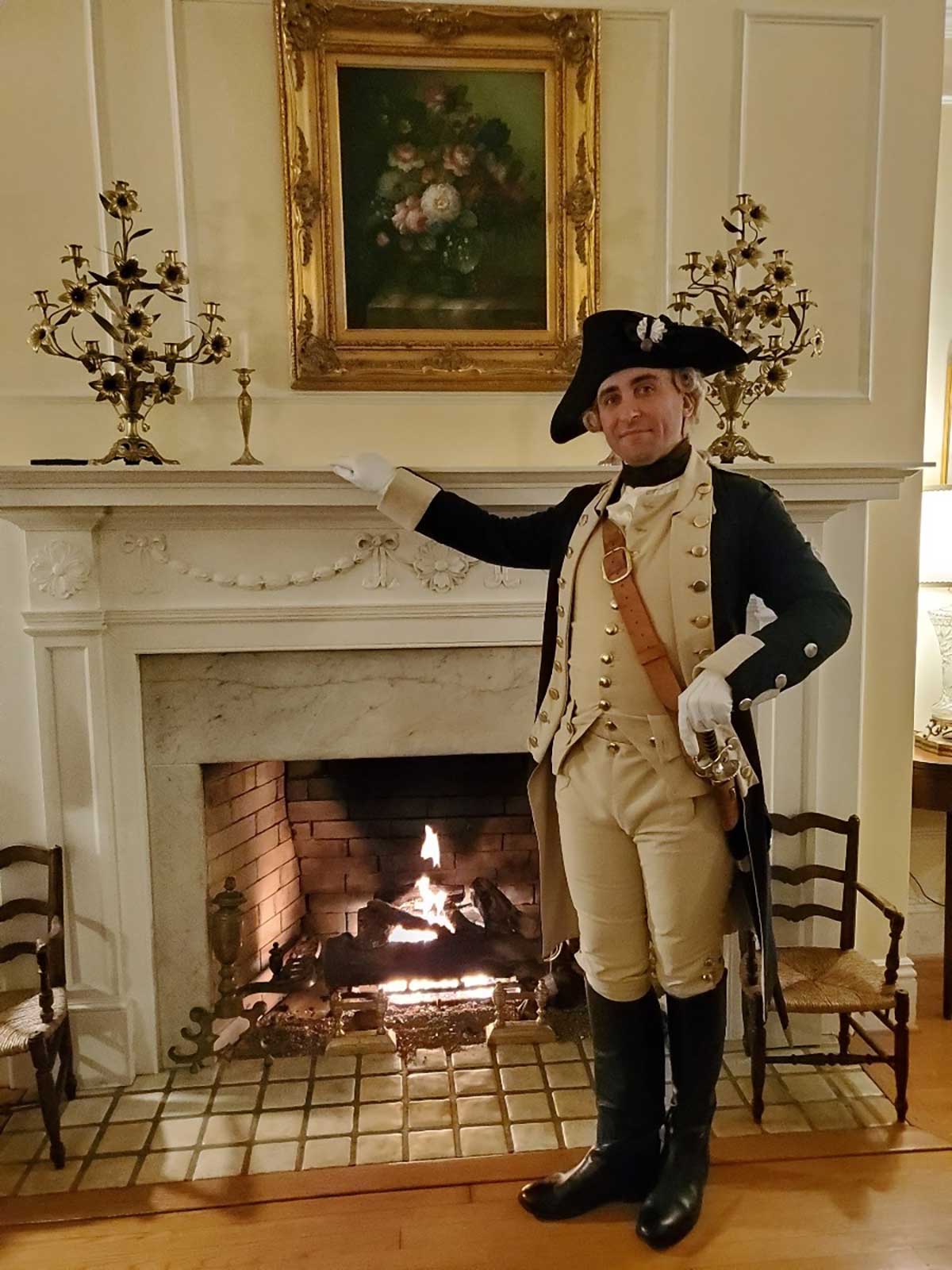 Reenactor standing in front of lit fire place at Hornsby Hosue Inn