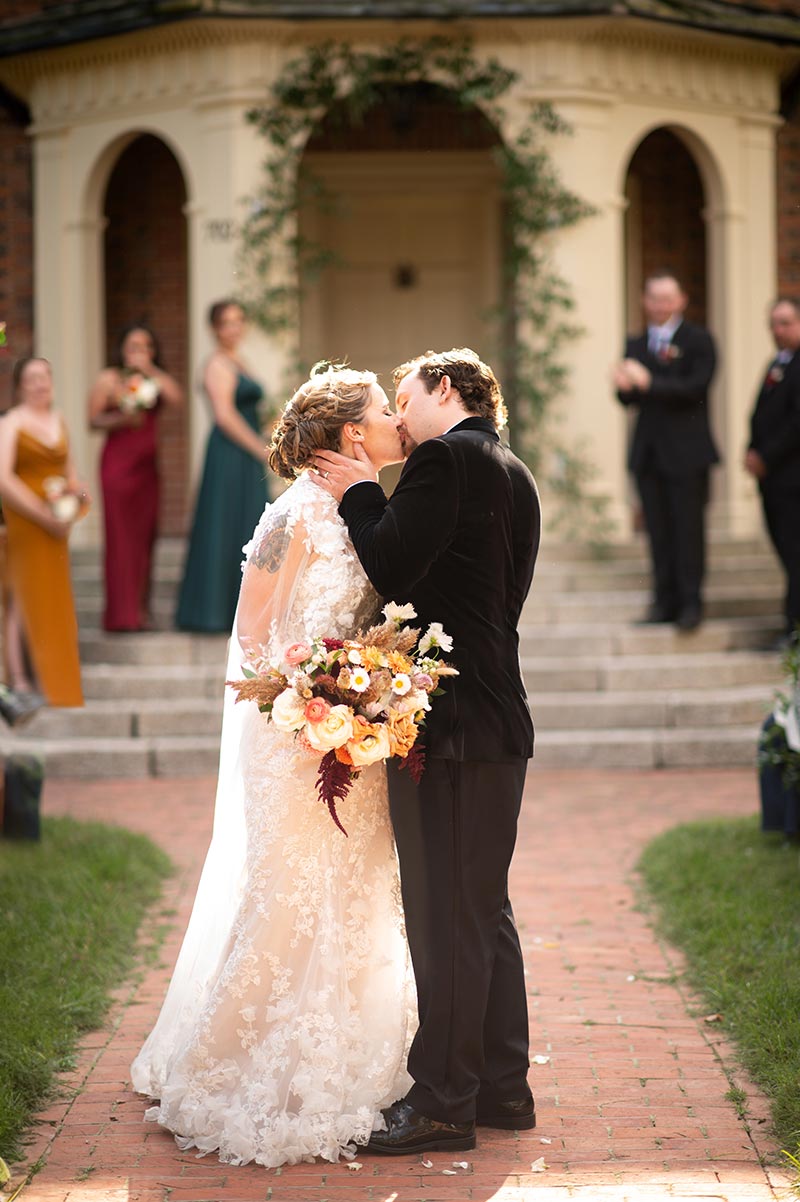 First kiss between a couple in a wedding at Hornsby House Inn on front walkway