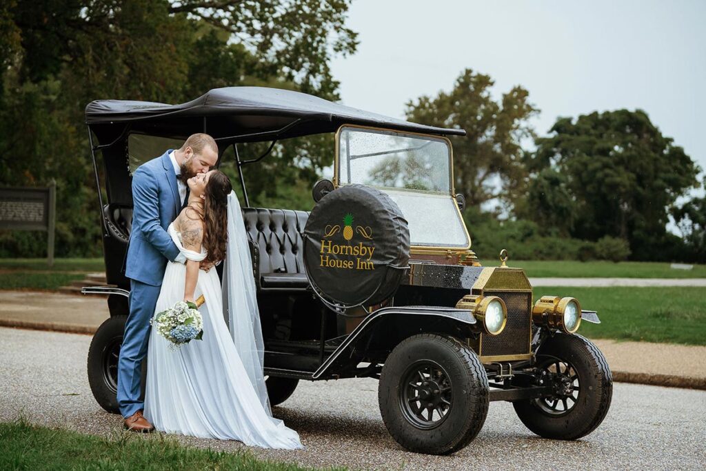 Bride and groom kiss by vintage Hornsby House Inn car