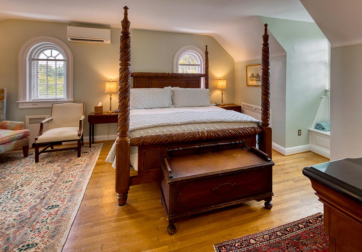 Carved four‑poster king bed with reading lamps in an attic suite at Hornsby House Inn