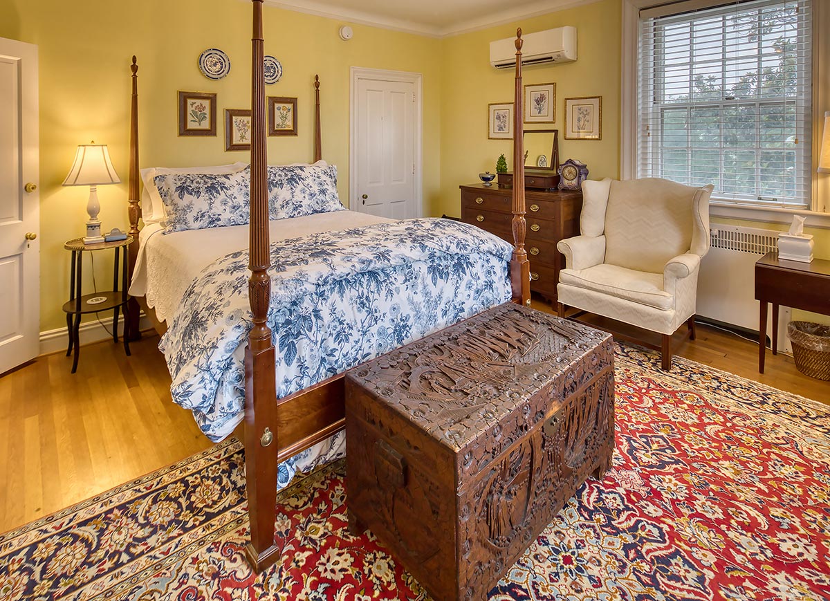 Queen bedroom with carved chest and blue floral bedding at Hornsby House Inn