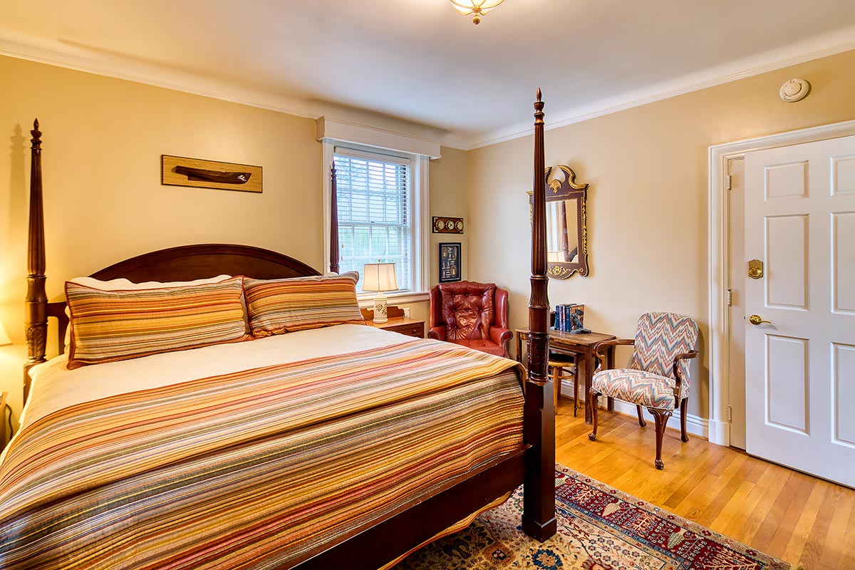 Cozy queen bedroom with four‑poster bed and reading chairs at Hornsby House Inn