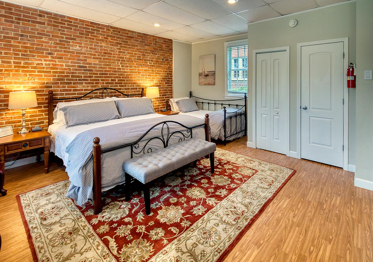 Garden king room with additional twin bed and exposed brick at Hornsby House Inn